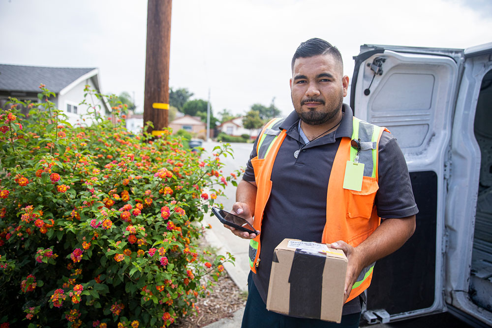 A young Hispanic man delivering packages in a residential neighborhood.